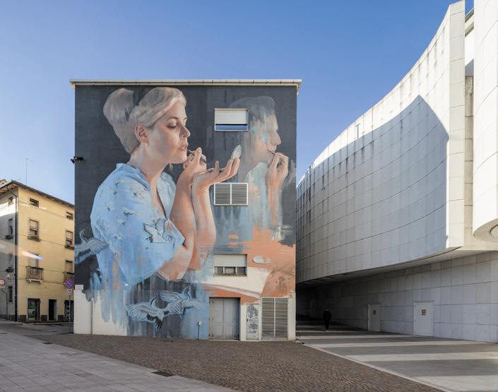 Großes Wandbild einer Frau an einer Hausfassade neben einem modernen Gebäude - Pordenone Kulturhauptstadt 2027