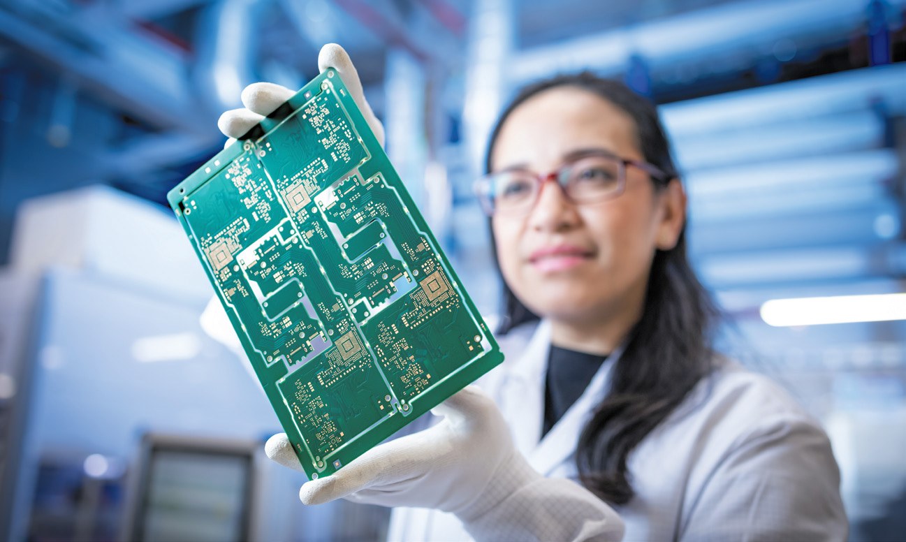 Mitarbeiterin in Reinraumkleidung hält eine Leiterplatte bei AT&S in Leoben – steirische Elektronikindustrie
