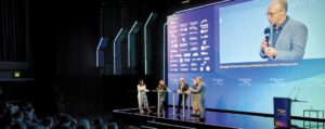 Podiumsdiskussion auf der Bühne der Technology Talks Austria 2026 vor großer Leinwand