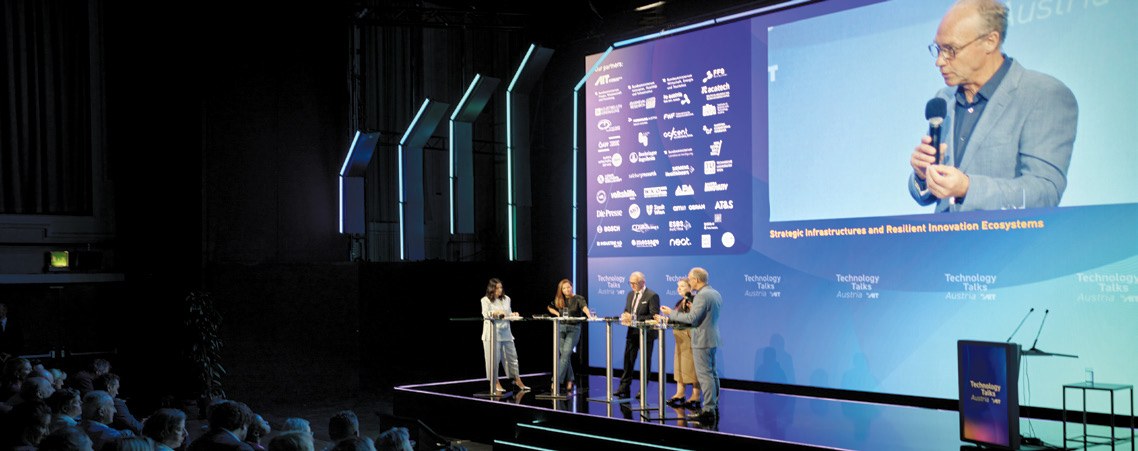 Podiumsdiskussion auf der Bühne der Technology Talks Austria 2026 vor großer Leinwand